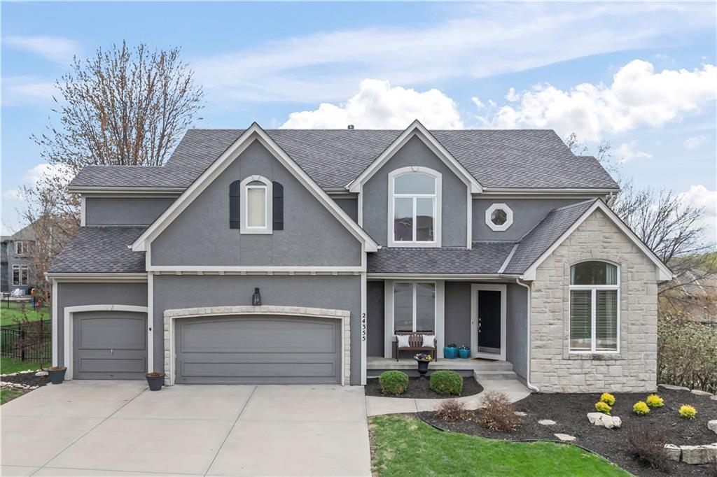 traditional home with concrete driveway, a porch, stone siding, and stucco siding
