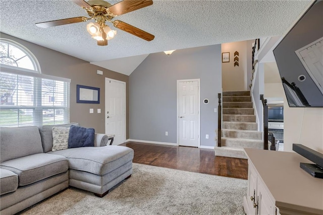 living area with a textured ceiling, a ceiling fan, vaulted ceiling, carpet floors, and stairway