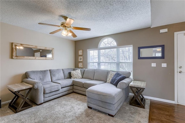 living area with a textured ceiling, baseboards, and a ceiling fan