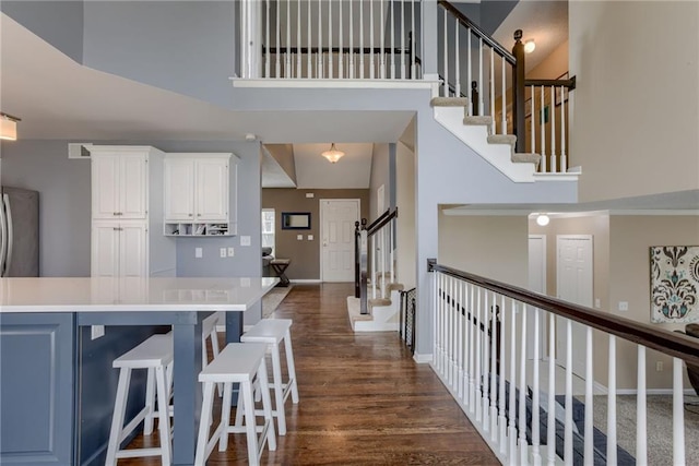 interior space featuring a towering ceiling, baseboards, visible vents, and wood finished floors