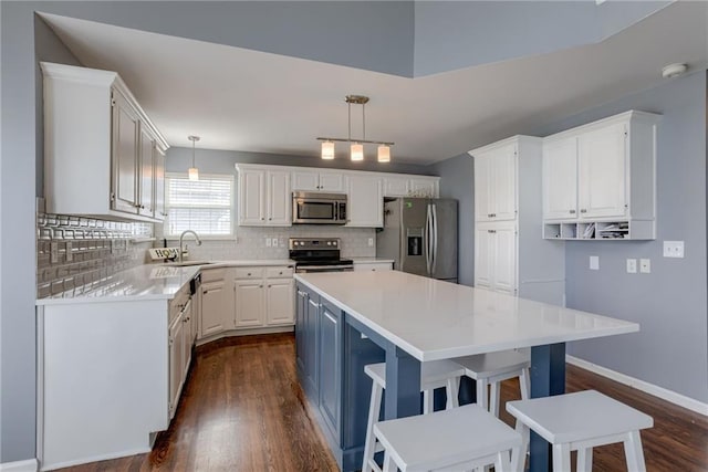 kitchen featuring white cabinetry, a kitchen island, dark wood finished floors, stainless steel appliances, and decorative backsplash