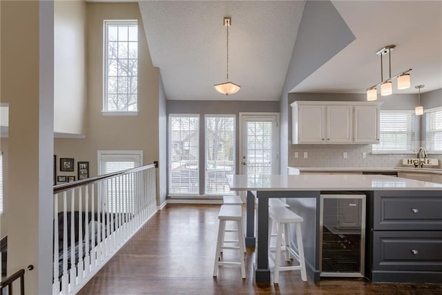 kitchen with dark wood-type flooring, beverage cooler, light countertops, and gray cabinets