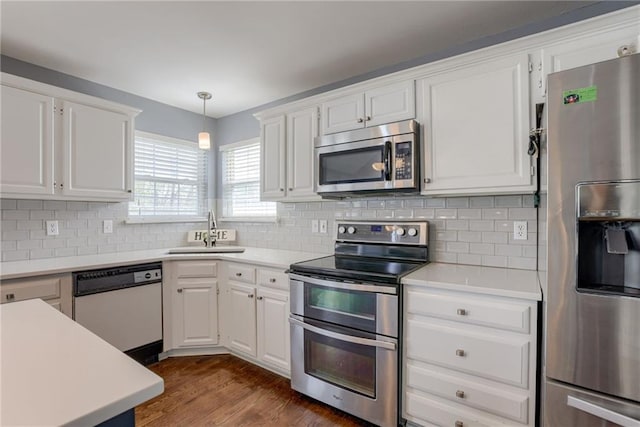kitchen with white cabinets, appliances with stainless steel finishes, light countertops, a sink, and decorative backsplash