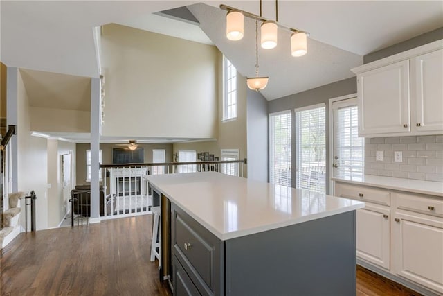 kitchen featuring vaulted ceiling, a center island, light countertops, and white cabinetry