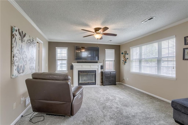 carpeted living area featuring a fireplace with flush hearth, crown molding, and ceiling fan
