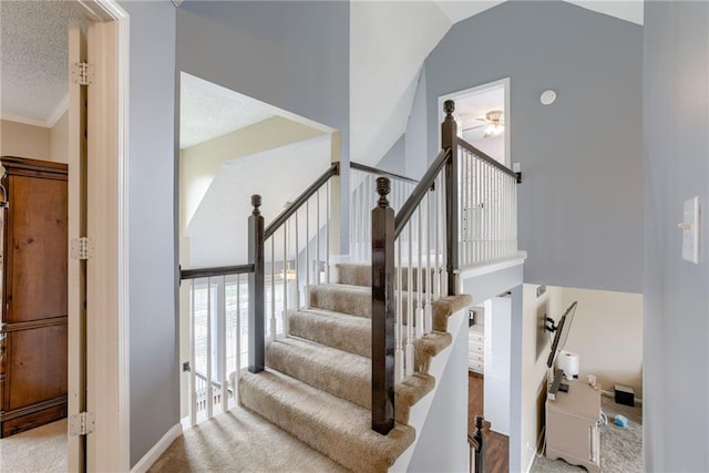 stairs featuring ornamental molding, a textured ceiling, a ceiling fan, high vaulted ceiling, and carpet