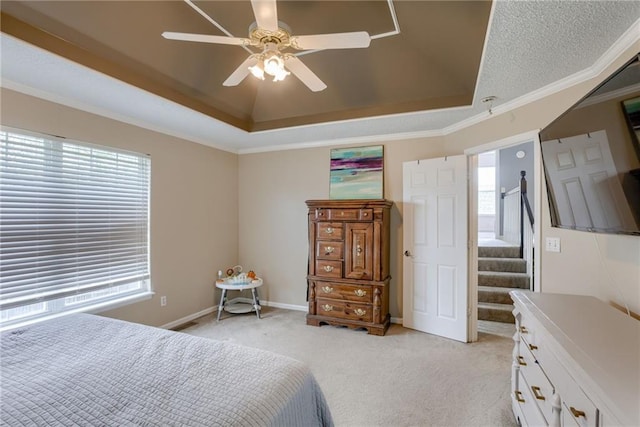 bedroom featuring a tray ceiling, ornamental molding, a ceiling fan, light carpet, and baseboards