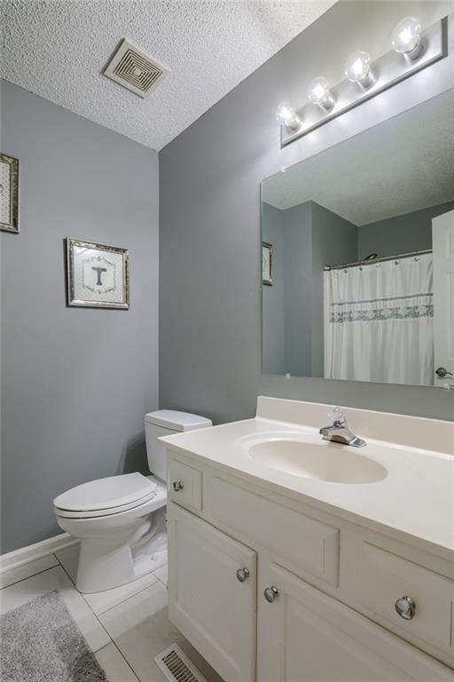 full bath with vanity, tile patterned floors, a textured ceiling, toilet, and visible vents