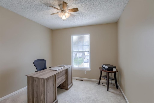 office space featuring visible vents, baseboards, a ceiling fan, a textured ceiling, and light carpet