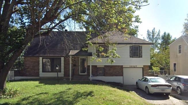 13327 Donnelly Ave, Grandview, MO 64030 - tri-level home with aphalt driveway, an attached garage, brick siding, and a front lawn