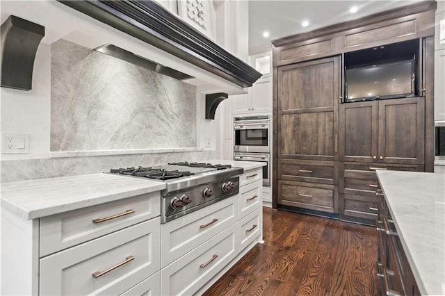 10408 Howe Ln, Leawood, KS 66206 - kitchen featuring dark wood-style flooring, light stone countertops, stainless steel appliances, white cabinetry, and under cabinet range hood