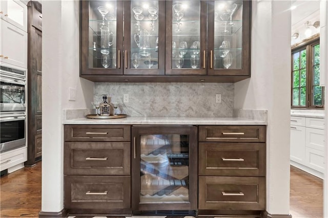 10408 Howe Ln, Leawood, KS 66206 - bar featuring decorative backsplash, stainless steel double oven, a dry bar, wine cooler, and dark wood-type flooring