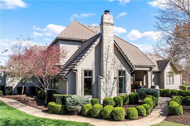 10408 Howe Ln, Leawood, KS 66206 - view of property exterior featuring a tiled roof, a chimney, and stucco siding