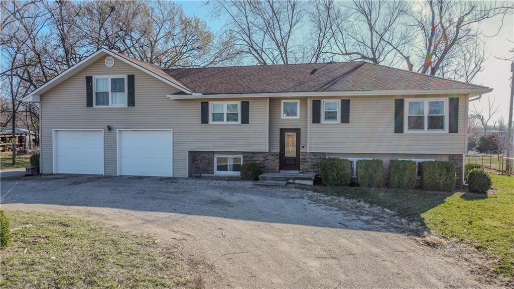 raised ranch featuring an attached garage and driveway