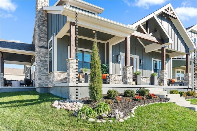 view of front of home featuring a porch, stone siding, board and batten siding, and a front yard