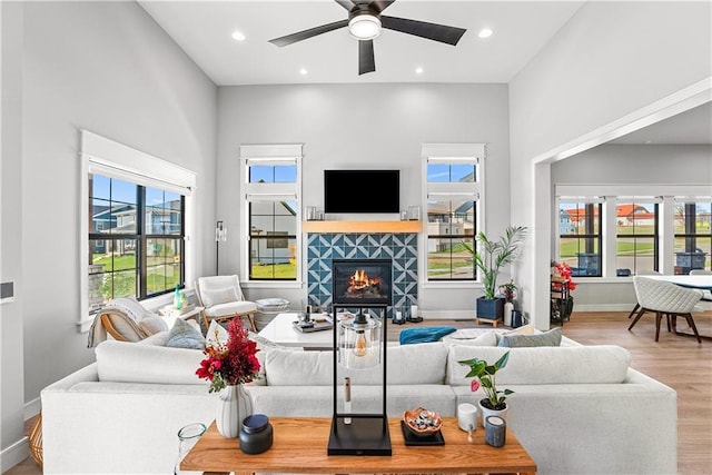 living room with wood finished floors, baseboards, recessed lighting, a tile fireplace, and ceiling fan