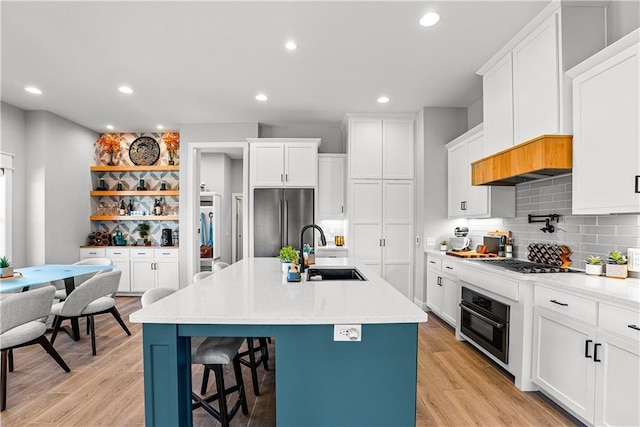 kitchen featuring a sink, a breakfast bar, light wood-style floors, and stainless steel appliances