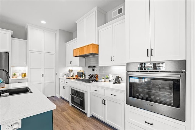 kitchen featuring a sink, visible vents, appliances with stainless steel finishes, and white cabinetry