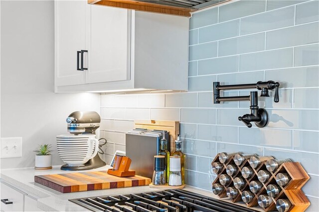room details featuring decorative backsplash and white cabinets