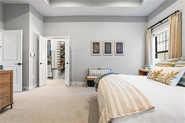 bedroom with a tray ceiling, baseboards, and light carpet