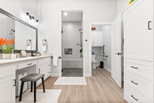 bathroom with vanity, toilet, a shower stall, and wood tiled floor