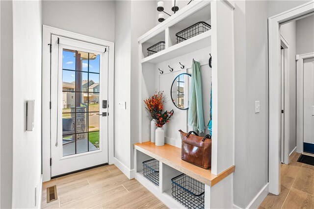mudroom with baseboards, visible vents, and wood finish floors