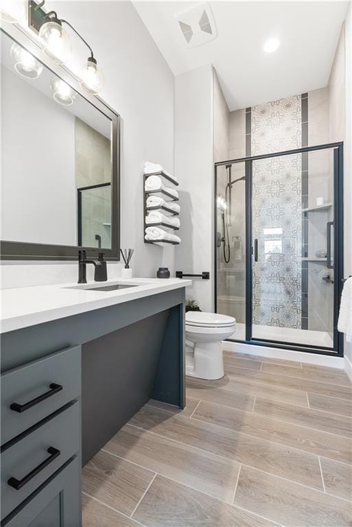 full bath with visible vents, wood finish floors, toilet, a stall shower, and vanity