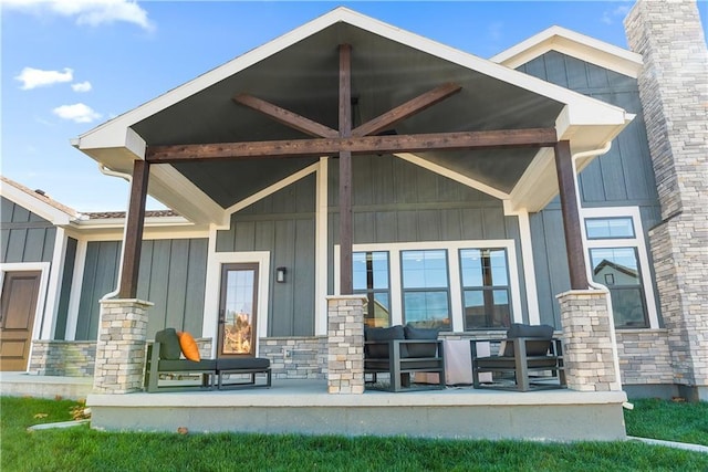 doorway to property featuring a porch, board and batten siding, stone siding, and a chimney