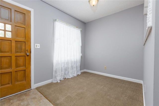 foyer with carpet, a textured ceiling, and baseboards