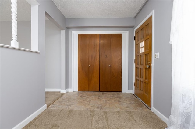 entryway featuring a textured ceiling, carpet flooring, and baseboards