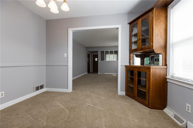 interior space featuring visible vents, carpet, a notable chandelier, and a healthy amount of sunlight