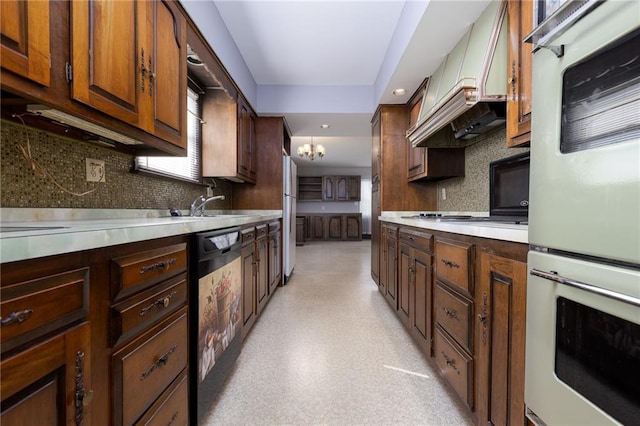 kitchen featuring custom exhaust hood, tasteful backsplash, light countertops, a notable chandelier, and black dishwasher