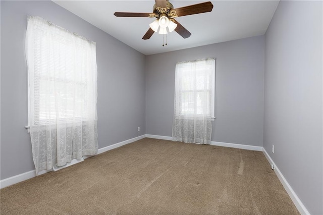 carpeted empty room with a healthy amount of sunlight, baseboards, and ceiling fan