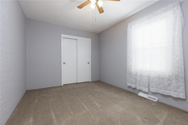unfurnished bedroom featuring a closet, multiple windows, visible vents, and carpet