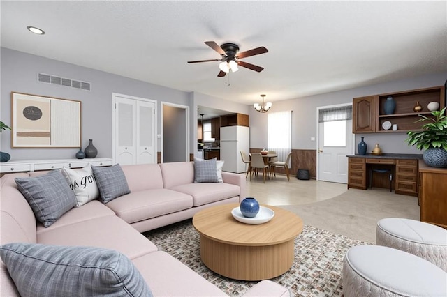 living area featuring visible vents, light colored carpet, and ceiling fan with notable chandelier