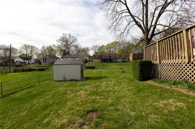 view of yard featuring fence, a storage shed, a residential view, an outdoor structure, and a deck