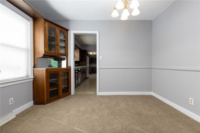 carpeted empty room with a healthy amount of sunlight, baseboards, and visible vents