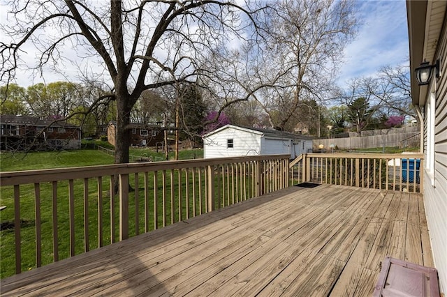 wooden terrace featuring an outdoor structure, a lawn, and fence