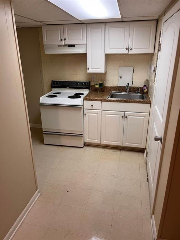 kitchen featuring dark countertops, white range with electric cooktop, under cabinet range hood, a paneled ceiling, and a sink