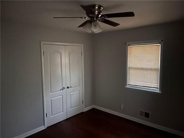 unfurnished bedroom with visible vents, a ceiling fan, a closet, baseboards, and dark wood-style flooring