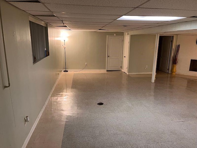 finished basement featuring a paneled ceiling and baseboards