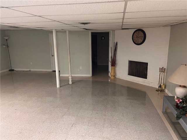 finished basement with tile patterned floors, a fireplace, a paneled ceiling, and baseboards