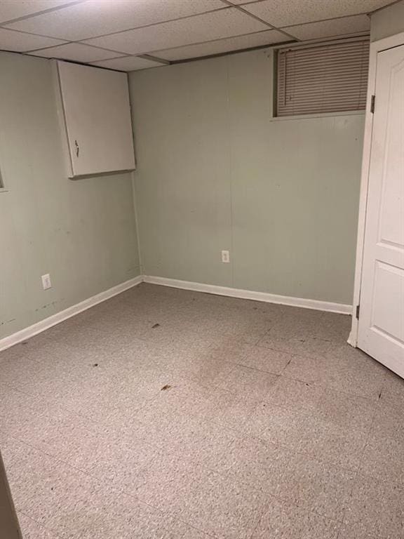interior space featuring tile patterned floors, a paneled ceiling, and baseboards