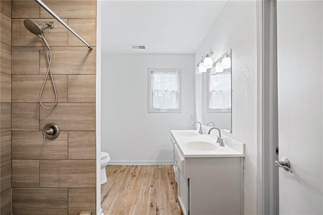 4001 E 55th St, Kansas City, MO 64130 - full bath featuring wood finished floors, a sink, double vanity, a tile shower, and visible vents