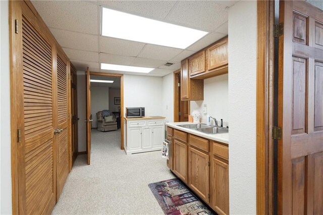 327 E Partridge Ave, Independence, MO 64055 - kitchen with a sink, light countertops, a paneled ceiling, stainless steel microwave, and light colored carpet