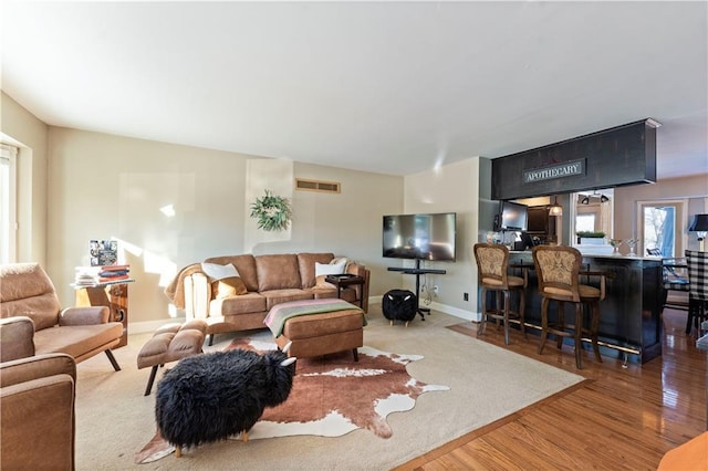 living room with baseboards, wood finished floors, and visible vents