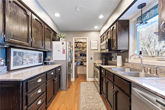 kitchen featuring dark brown cabinetry, appliances with stainless steel finishes, a sink, and light wood finished floors