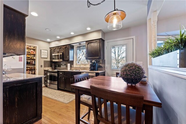 kitchen featuring appliances with stainless steel finishes, hanging light fixtures, dark brown cabinets, light wood-style floors, and recessed lighting