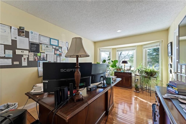 office area with light wood-style flooring and a textured ceiling