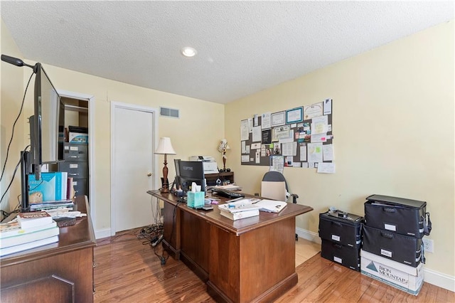 home office with a textured ceiling, visible vents, light wood-type flooring, baseboards, and recessed lighting